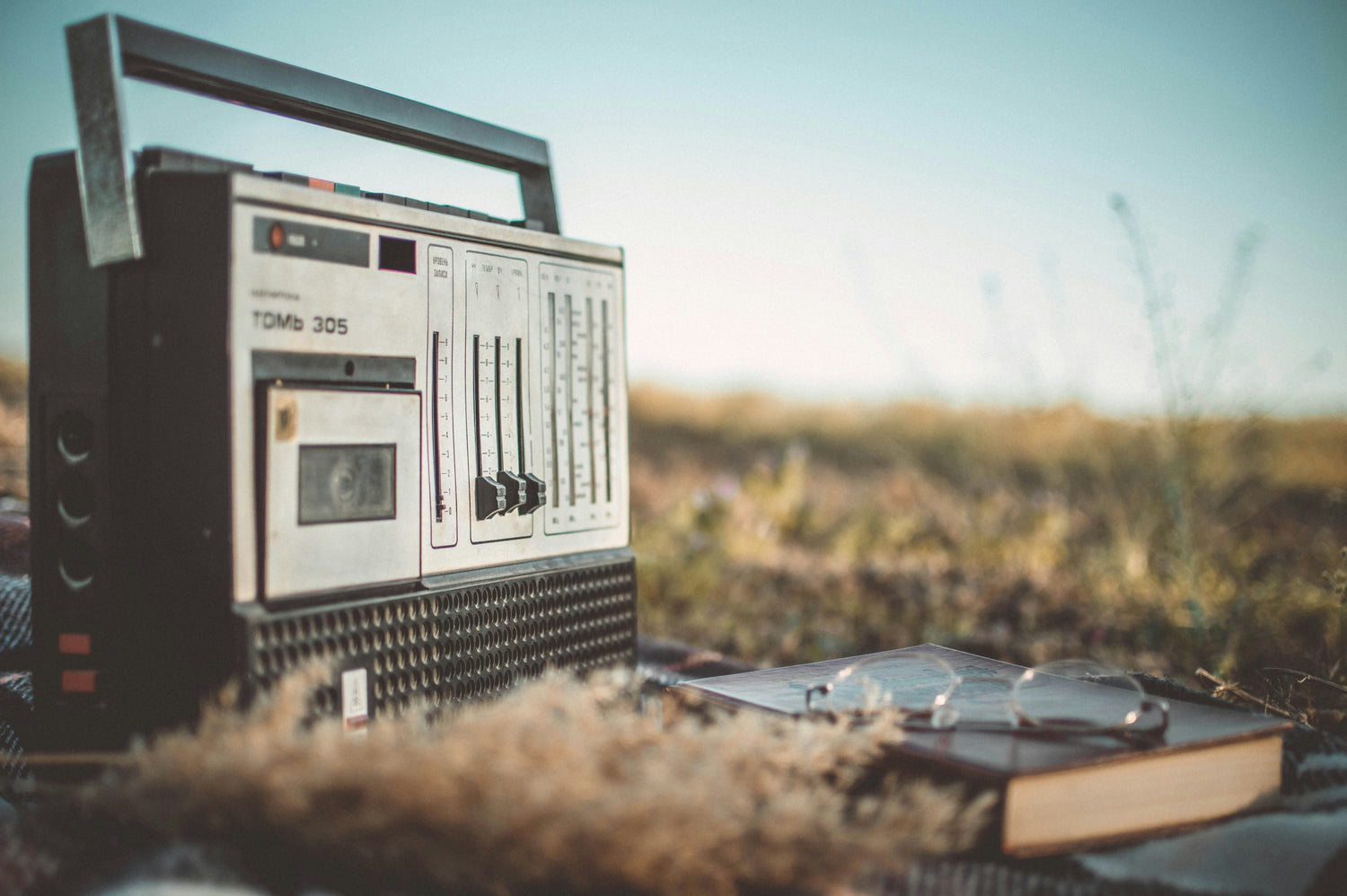Handheld Cassette player, a book and reading glasses on grass 