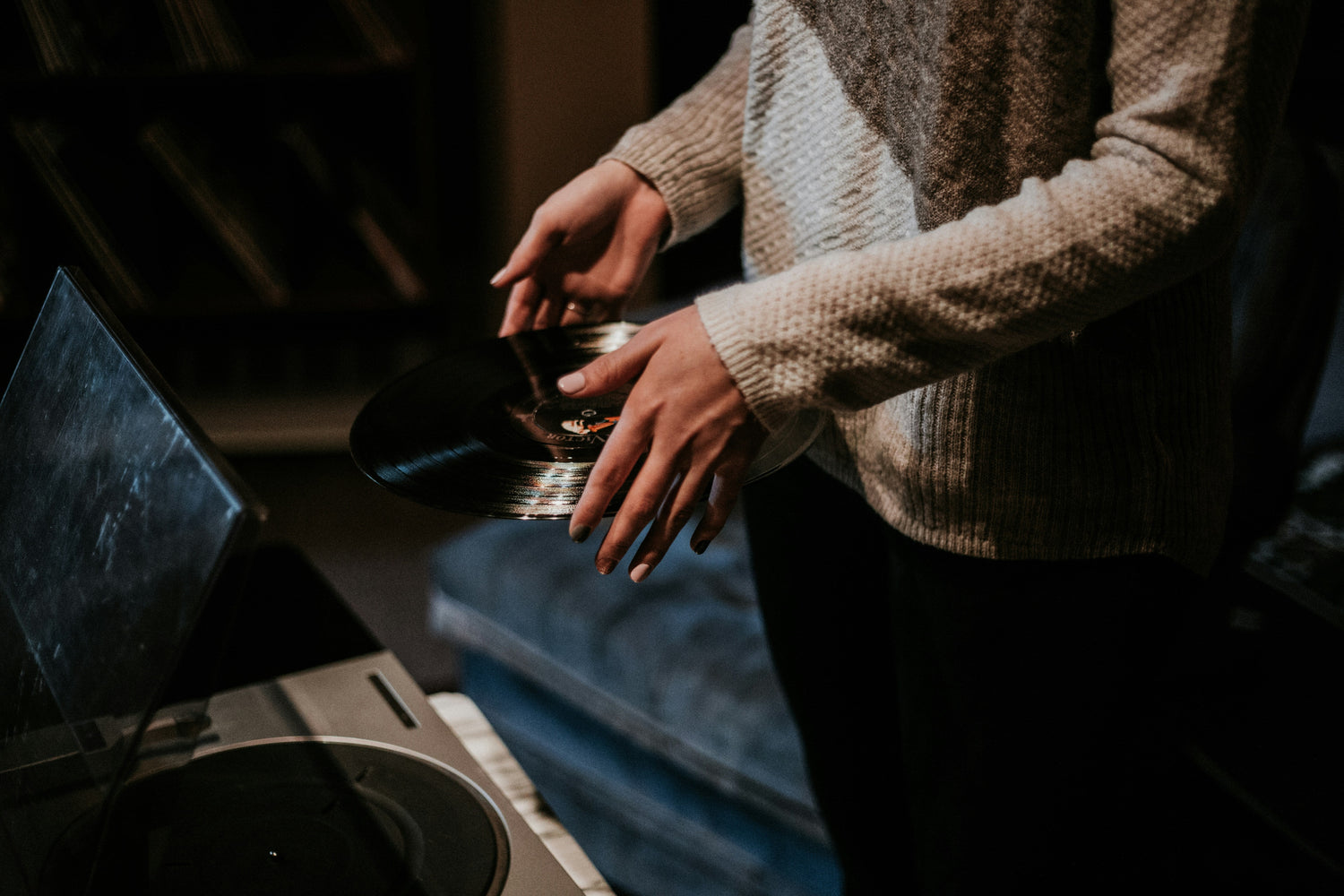 Hands holding a vinyl record next to a turntable 