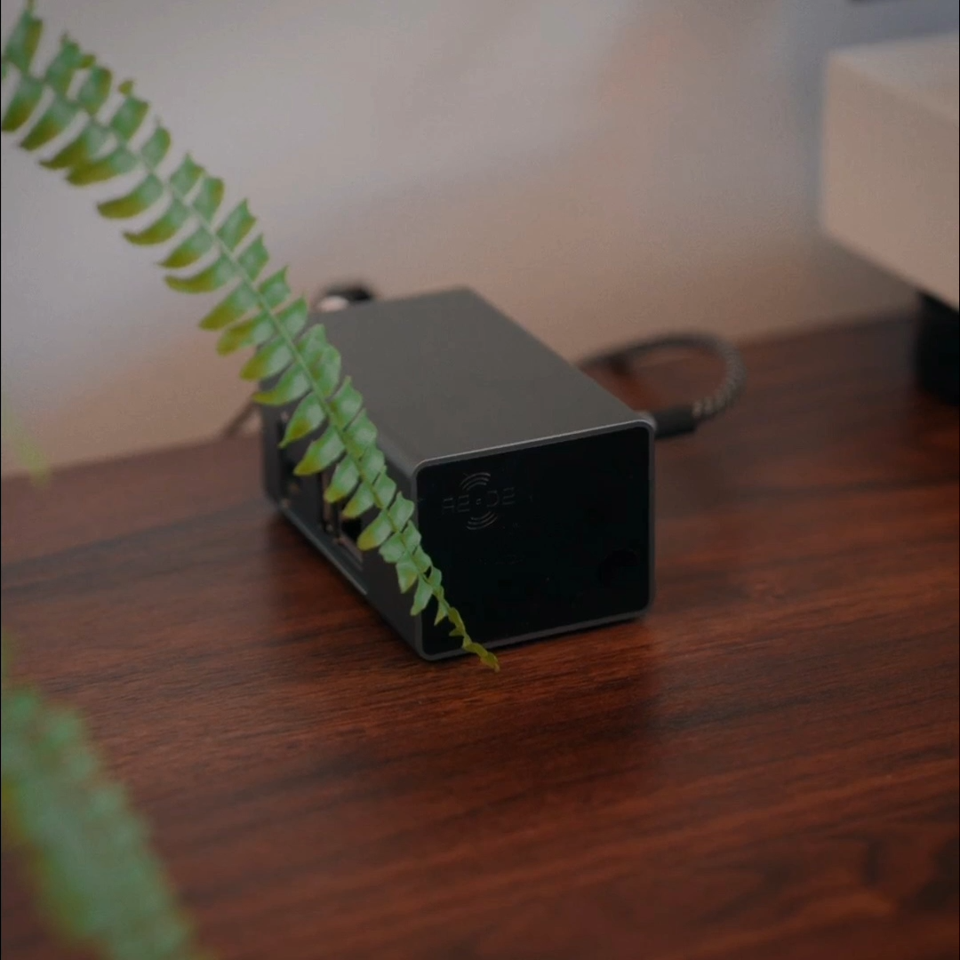 The A2D2 Stream on a wooden side table, showing its compact dark machined enclosure